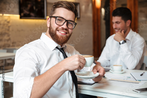 Portrait of a smiling bearded businessman drinking coffee