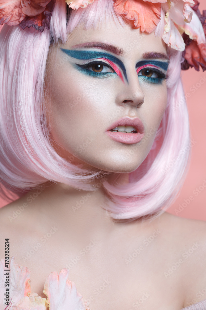Fashion beauty portrait of a beautiful girl with pink hair, creative make-up and a wreath of gladiolus on her head.