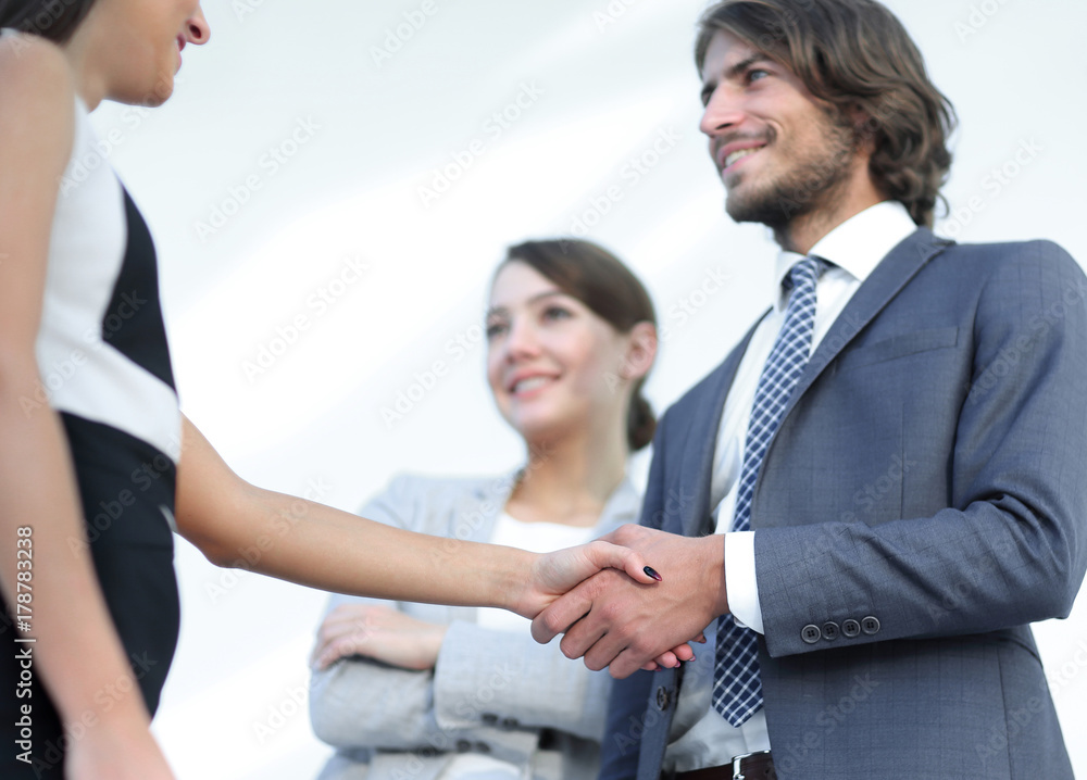 Businesspeople  shaking hands against room with large window loo