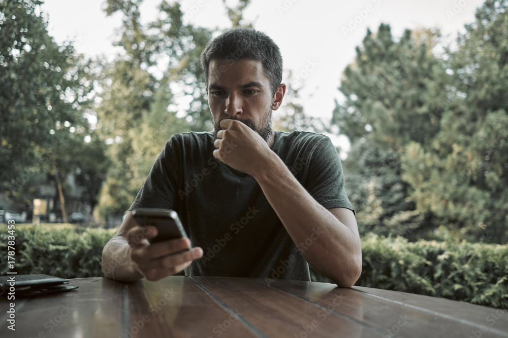 Communicates on the phone with friends. Blurred background of the park. Green Tones Communicates on the phone with friends. Blurred background of the park. Green Tones