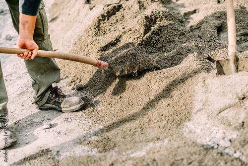 Industrial worker wearing protective gear using shovel on construction site