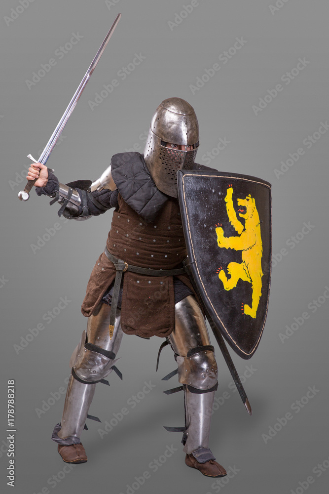 Fototapeta premium knight in breaths in a helmet with a sword and shield in battle over grey background