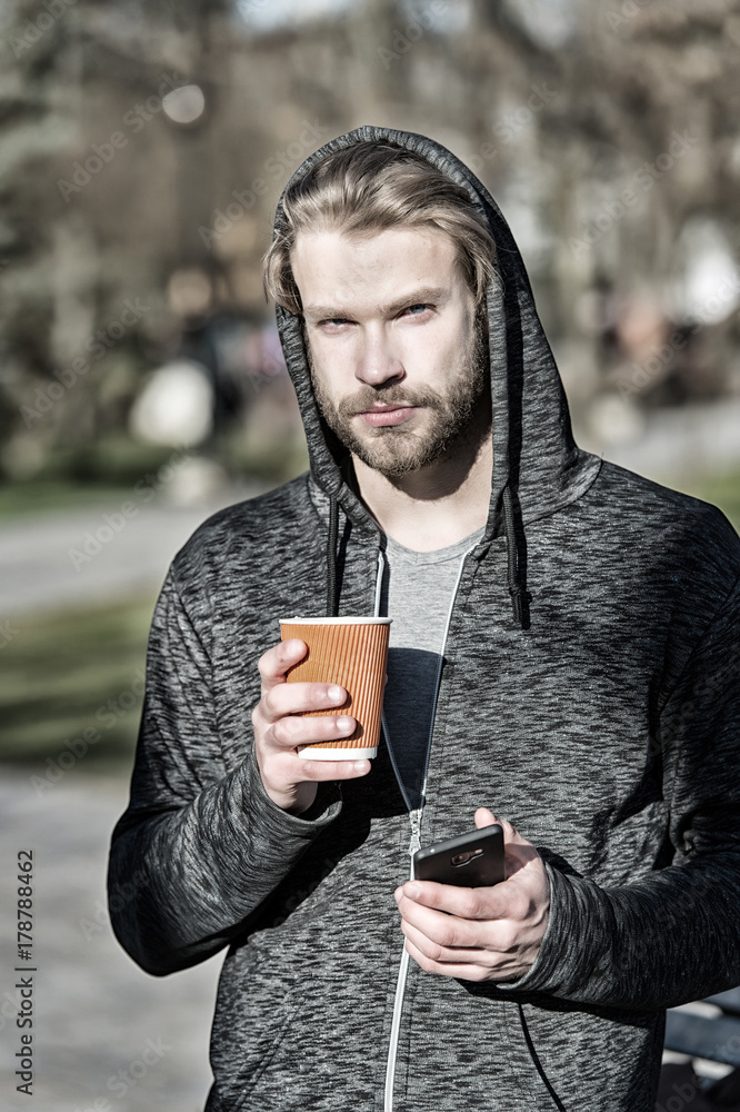 Man holding mobile phone and paper cup in park Man holding mobile phone and paper cup in park
