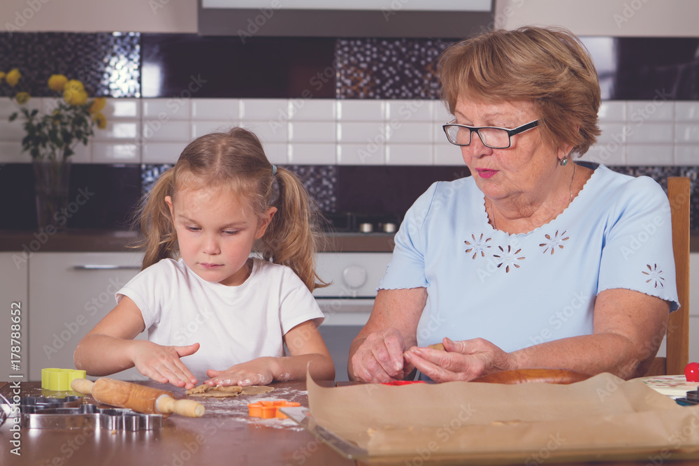little girl and grandmother roll out the dough little girl and grandmother roll out the dough