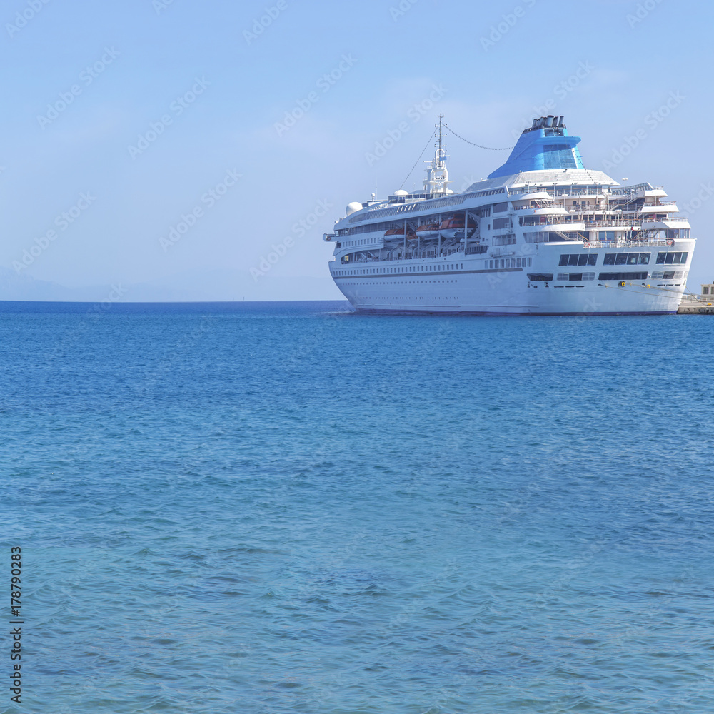 Big modern luxury cruise ship docked at marina dock with sea background