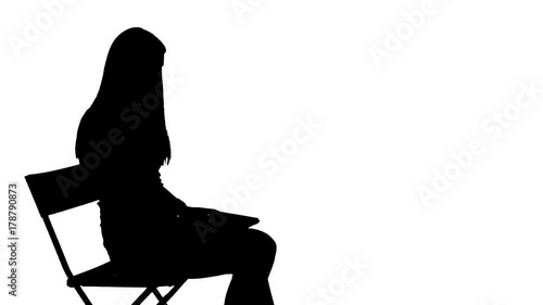 Woman sits down on a chair and using a laptop silhouette
