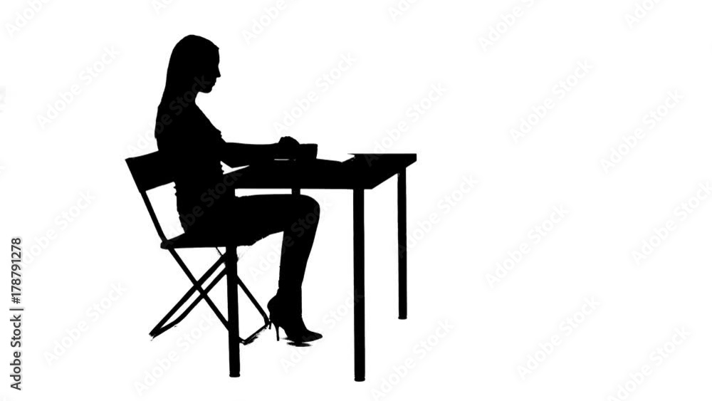 Girl sits down at the table drinks tea and uses a laptop silhouette Girl sits down at the table drinks tea and uses a laptop silhouette