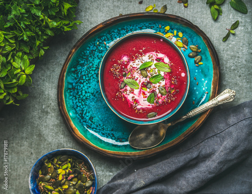 Spring detox beetroot soup with mint, chia, flax and pumpkin seeds on bright blue ceramic plate over grey concrete background, top view. Dieting, clean eating, weight loss, vegetarian food concept