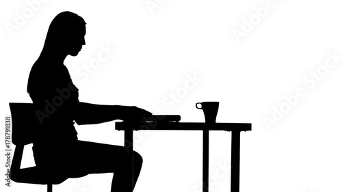 Female sits down at the table drinks coffee and uses a laptop silhouette