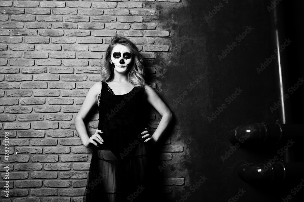 Halloween skull make up girl wear in black against brick wall at studio. Halloween skull make up girl wear in black against brick wall at studio.