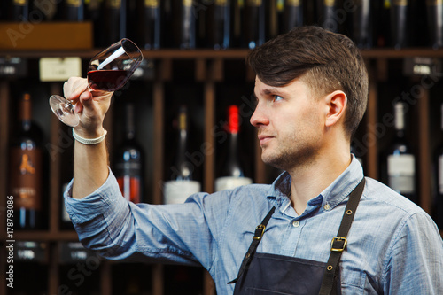 Bokal of red wine on background, male sommelier appreciating drink photo