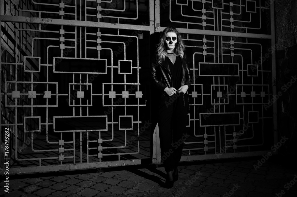 Halloween skull make up girl wear in black at night street of city against cage. Halloween skull make up girl wear in black at night street of city against cage.