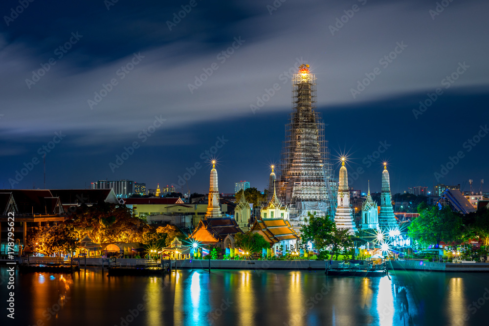Wat Arun Temple beside Chao Phraya River at twilight time in Bangkok, Thailand. One of the most famous place of Thailand's landmarks. Light reflection on smooth water.