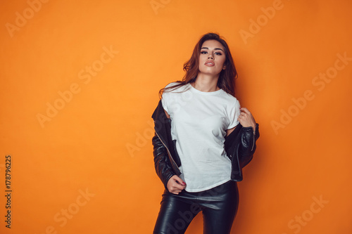 Sexy woman in white t-shirt and jacket on the orange background. Mock-up.