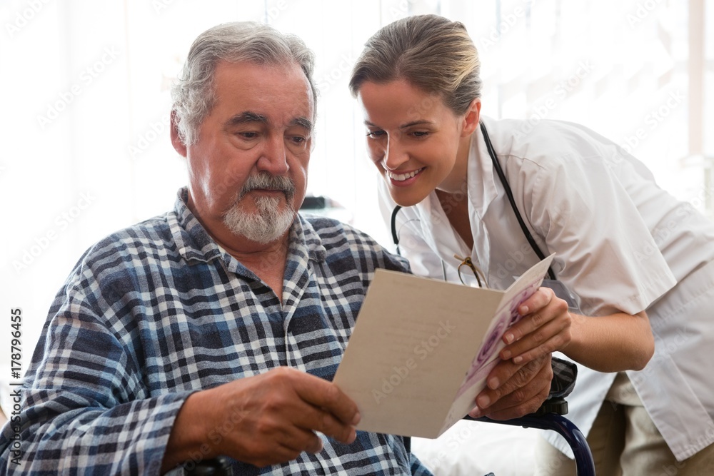 Female doctor showing greeting card to patient sitting on