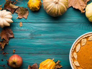 Autumn fall still life background on dark green wooden table. Pumpkins, leaves, traditional thanksgiving pumpkin pie