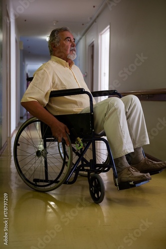 Thoughtful senior man sitting on wheelchair in corridor © WavebreakMediaMicro