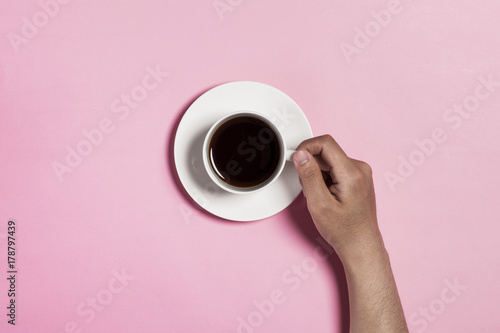 man hand hold a coffee cup on the pink background.
