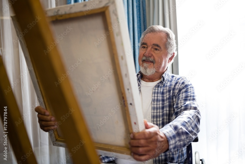 Senior man looking at painting while sitting on wheelchair Senior man looking at painting while sitting on wheelchair