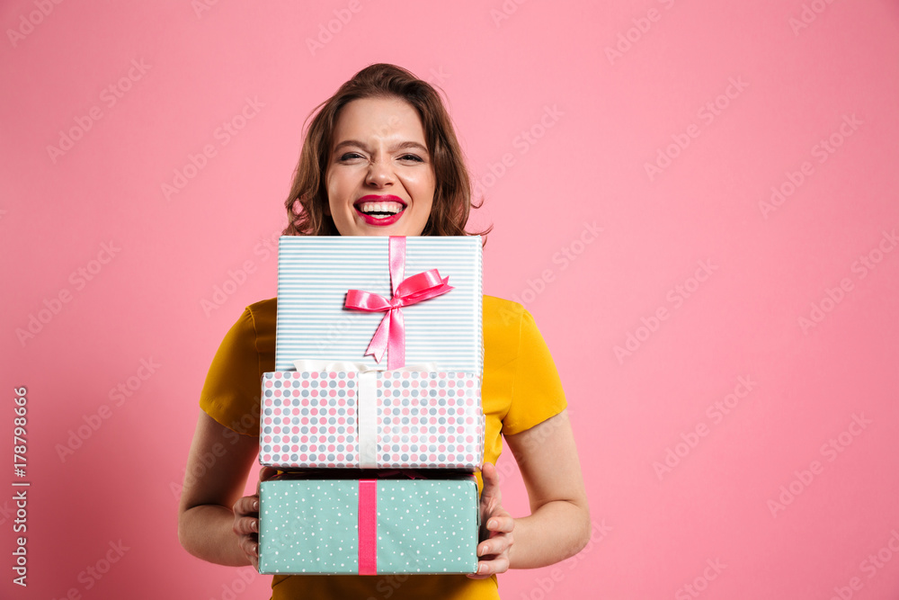 Happy laughing woman with red lips holding bunch of gift boxes, looking at camera Happy laughing woman with red lips holding bunch of gift boxes, looking at camera