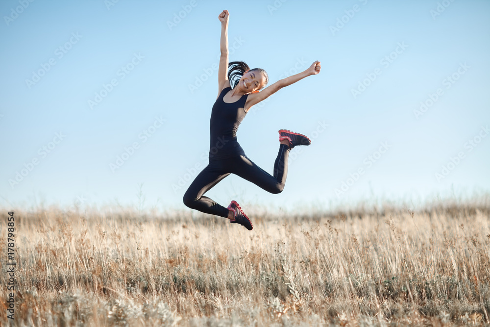 Young Asian woman in sports clothes happy jumping outdoors Young Asian woman in sports clothes happy jumping outdoors