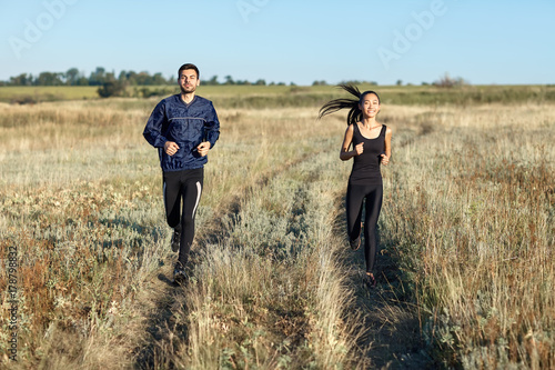 Man and woman in sportswear running in field