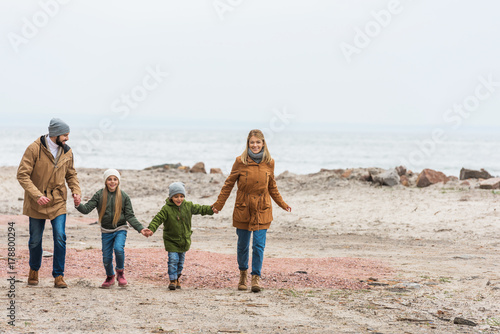 family holding hands and walking by seashore
