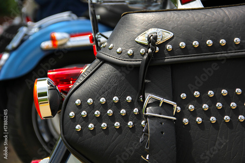 closeup of black leather motorcycle saddlebags with rhinestone studs, cruiser motorcycles in back photo