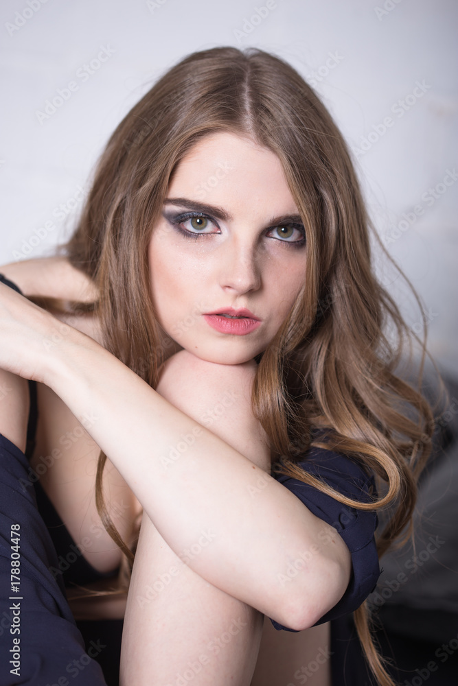 Portrait of attractive young woman resting her head over the knee. Half length. Indoors. Portrait of attractive young woman resting her head over the knee. Half length. Indoors.