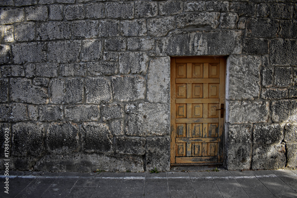 Old wooden door at brick stone wall as background