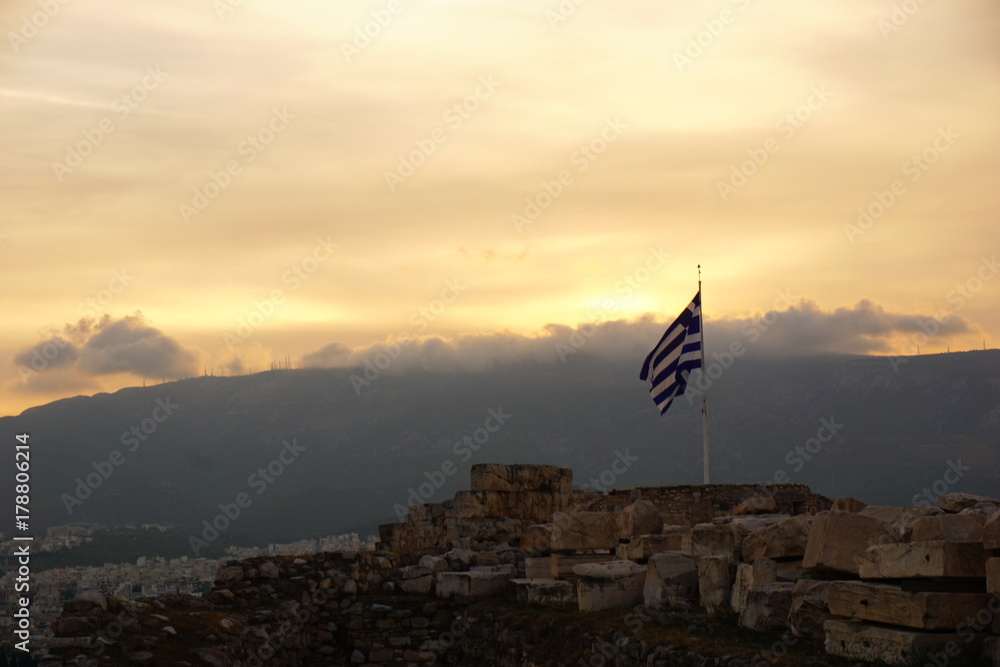 Greek Flag over City with gorgeous Sunset Sky and clouds & mountains Background