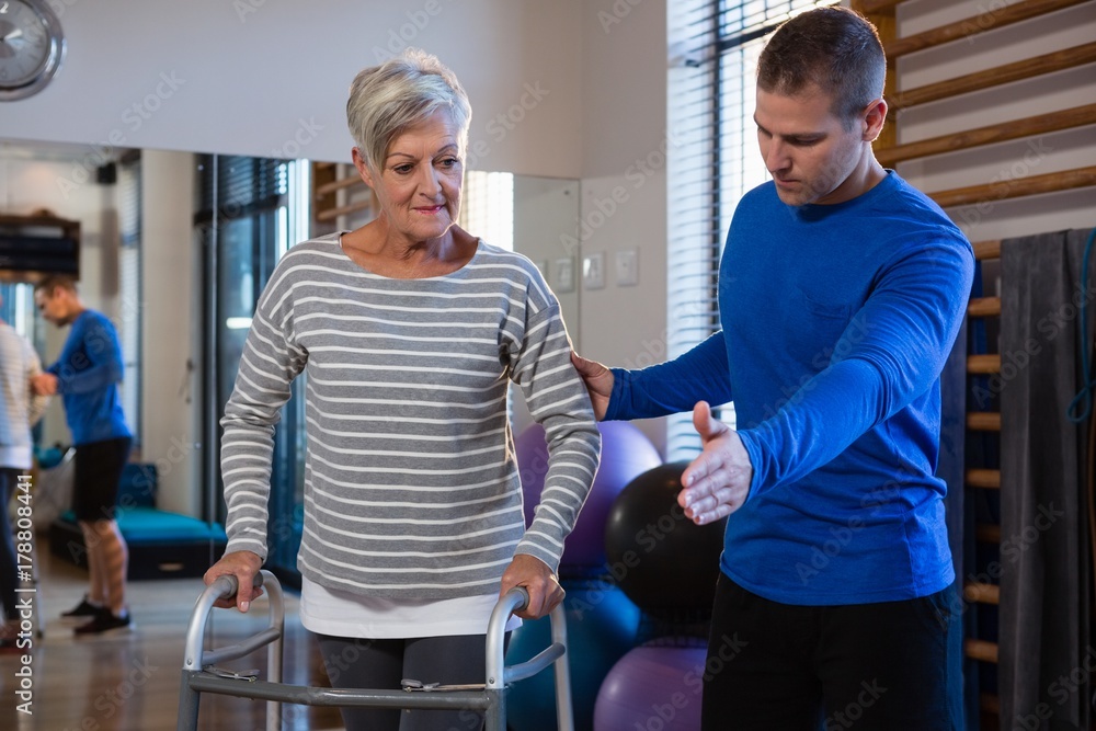 Obraz premium Man helping senior woman to walk with walker