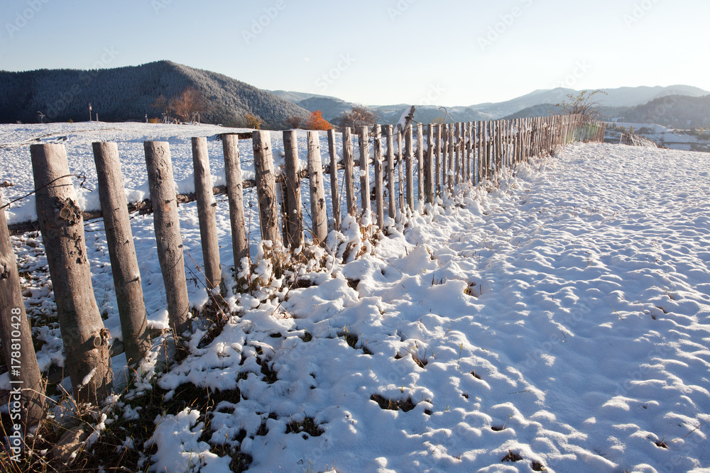 A wooden fence on a meadow with snow.