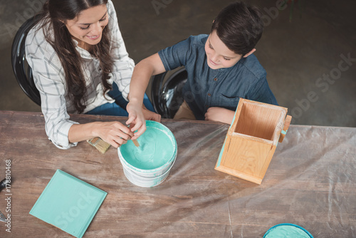Son and mother painting birdhouse