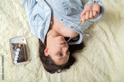 sensual young woman with sweet cake lying on bed