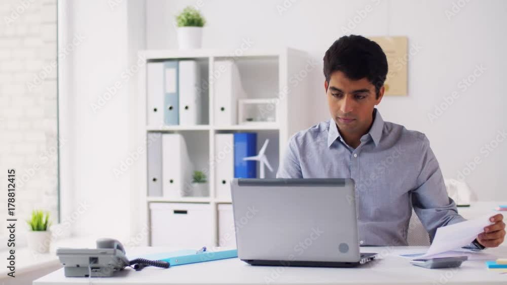 businessman with papers typing on laptop at office businessman with papers typing on laptop at office
