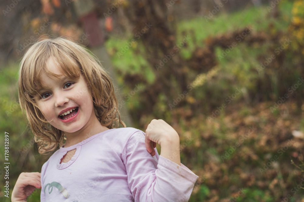 Young, blonde girl playing around in the backyard and smiling. Young, blonde girl playing around in the backyard and smiling.