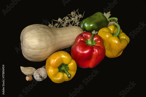 Large red,yellow,green sweet peppers with pumpkin, nuts and thorns on black background

