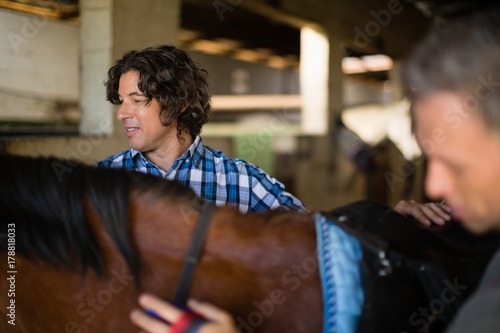 Man grooming the horse in the stable