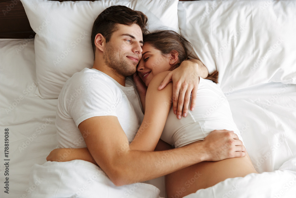 Cheerful pregnant woman lies in bed with husband Cheerful pregnant woman lies in bed with husband