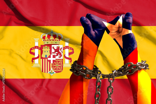 Two hands shackled a metal chain on the background of flags of Catalonia and Spain photo