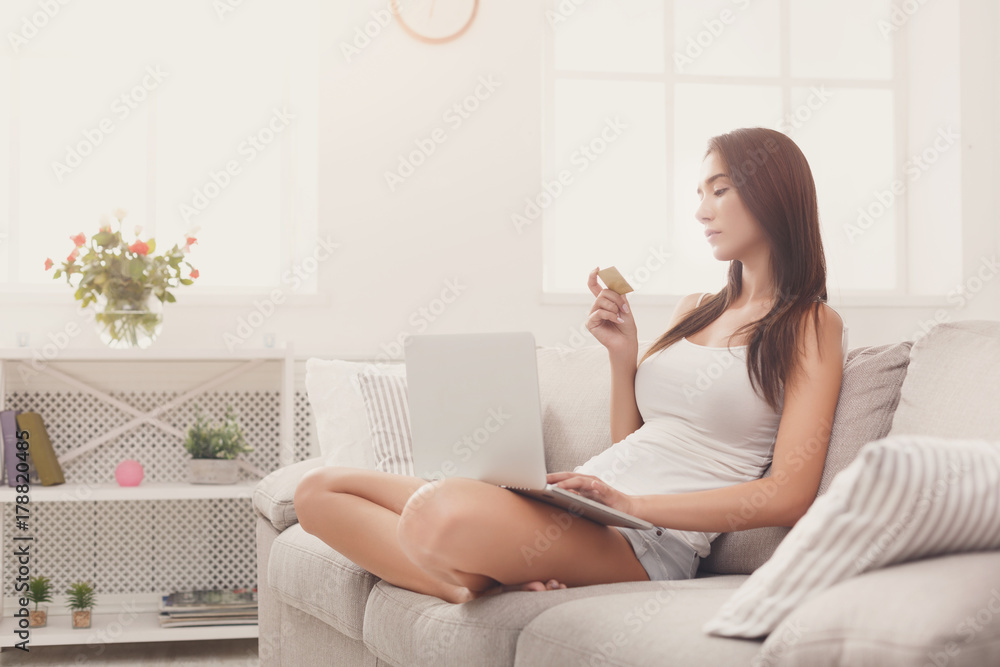 Pensive woman shopping online with credit card Pensive woman shopping online with credit card