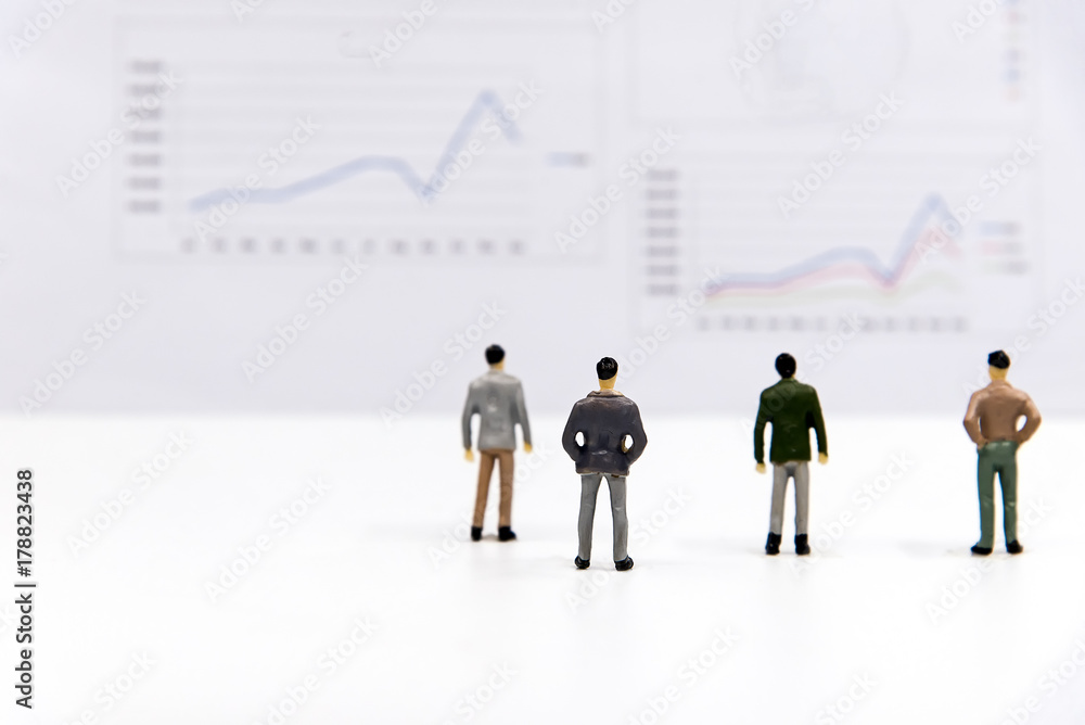 Miniature group businessman view the financial graph on the board and thinking with project for presenting investment. Investment and Business Concept. select focus Miniature group businessman view the financial graph on the board and thinking with project for presenting investment. Investment and Business Concept. select focus