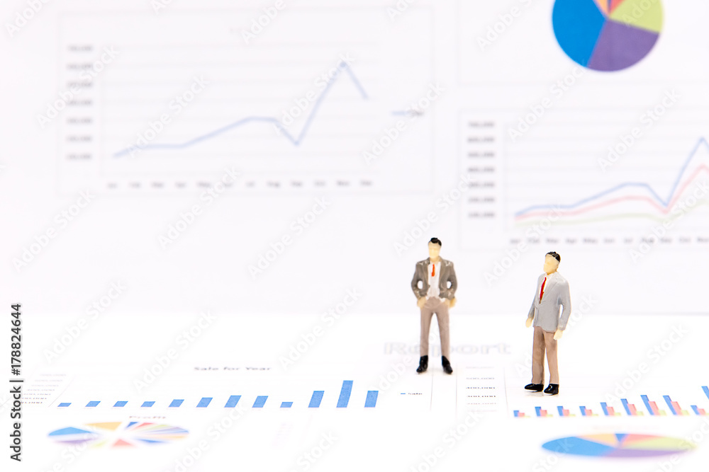 Miniature group businessman view the financial graph on the board and thinking with project for presenting investment. Investment and Business Concept. select focus Miniature group businessman view the financial graph on the board and thinking with project for presenting investment. Investment and Business Concept. select focus