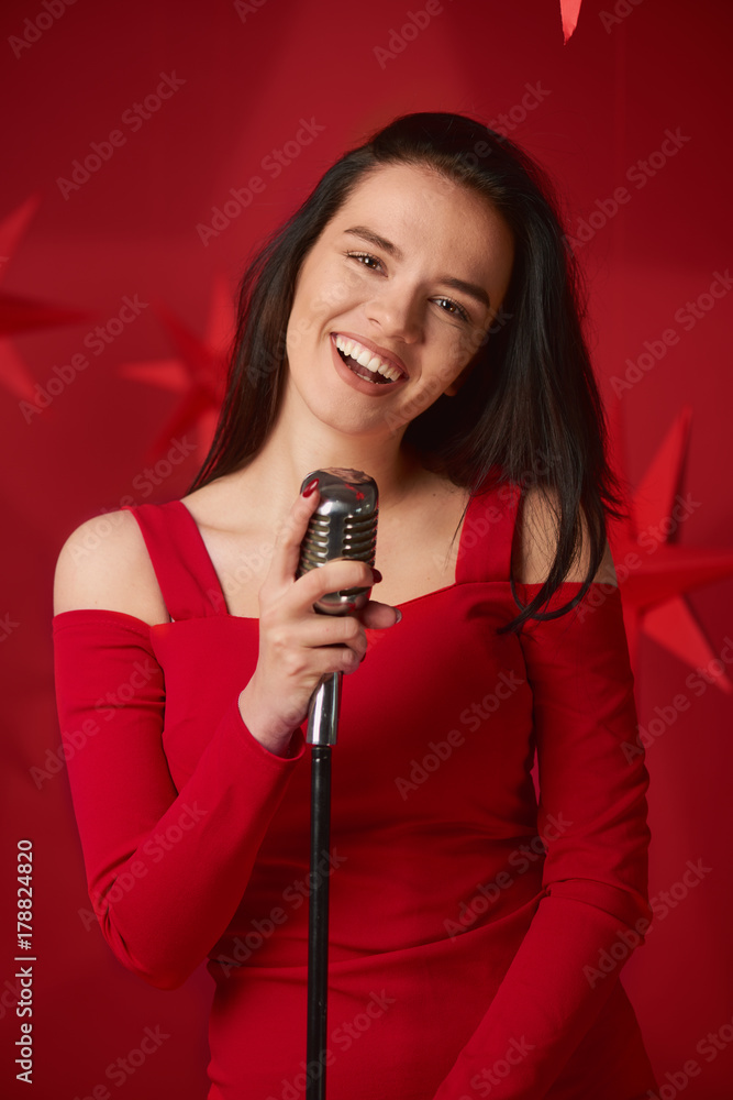 Girl singing and holding microphone. Red background and stars behind Girl singing and holding microphone. Red background and stars behind