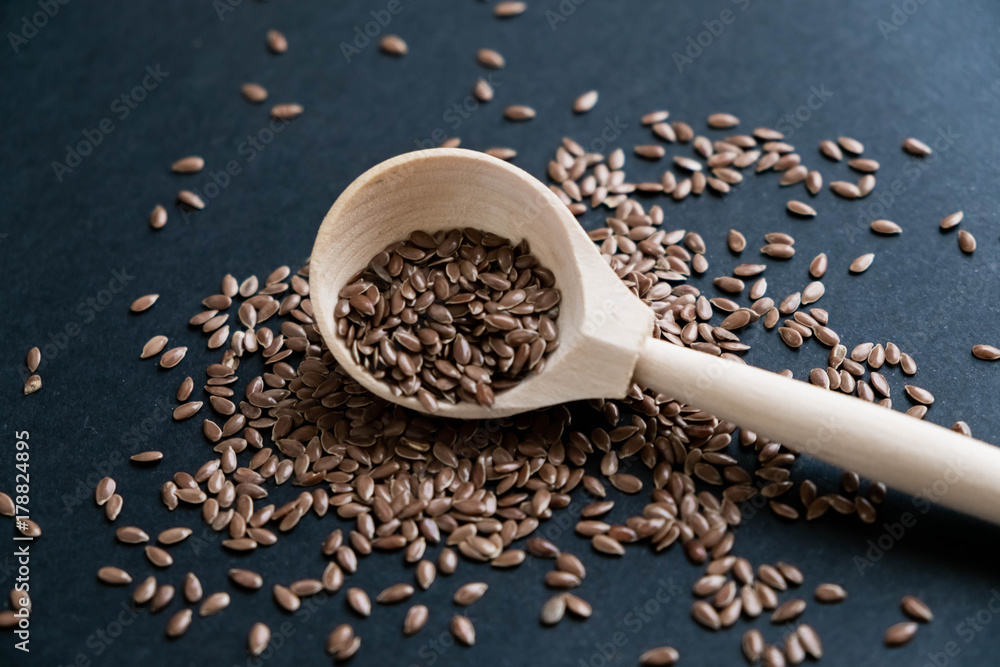 Flax seeds in spoons over dark background. Natural light. Selective focus. Close up on a black background. Top view, flat lay. copy space Flax seeds in spoons over dark background. Natural light. Selective focus. Close up on a black background. Top view, flat lay. copy space