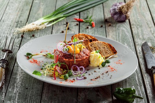 Tasty tartare with toasted bread and salad. Gourmet French meal made of raw ground meat. Delicious healthy food.