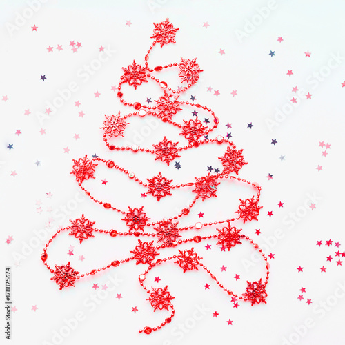 Christmas Tree made of red snowflake garland with silver star confetti. New Year symbol with place for text. Flat lay, top view.
