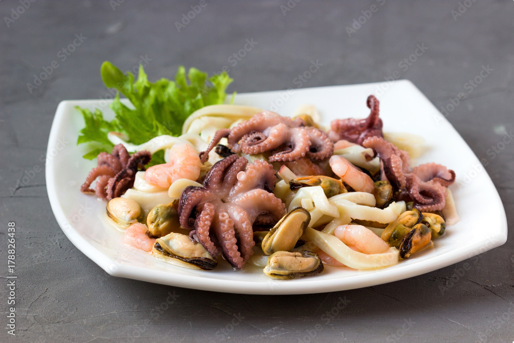 Green fresh lettuce with squid, octopus, shrimp's tails, mussels , on the white plate. Green fresh lettuce with squid, octopus, shrimp's tails, mussels , on the white plate.