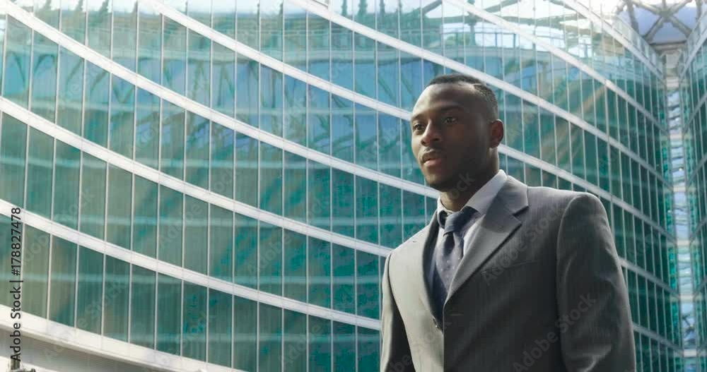 Portrait of a businessman looking at the future proud of his success and smiling. On skyscrapers background with glazed windows. Concept of: business, economy, finance, dreams, future. Portrait of a businessman looking at the future proud of his success and smiling. On skyscrapers background with glazed windows. Concept of: business, economy, finance, dreams, future.